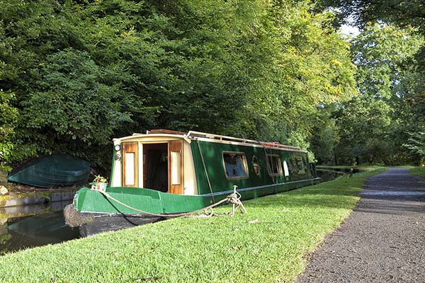 narrowboat docked by green trees and leaves